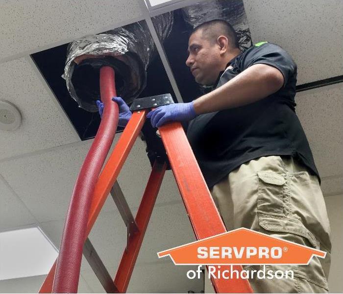 technician on red ladder clean a commercial air duct